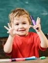 Toddler cute and cheerful ready to study. Kid boy in classroom near colorful markers, chalkboard on background, close up Royalty Free Stock Photo