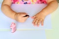 Toddler cute child in pink elegant dress sitting wood white table and making manicure