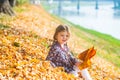 Toddler cute girl playing with autumn leaves. Falling maple leaves natural background. Fall outdoor background.