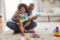 Toddler daughter sits on dadÃ¯Â¿Â½s knee playing ukulele at home Royalty Free Stock Photo