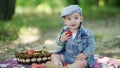 Toddler in denim suit and a cap holding apples in the hands