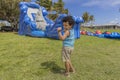 A toddler does his happy dance while watching a bounce house inflate