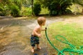 A toddler drinking water from a hose