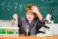 Toddler genius baby. Boy near microscope and test tubes in school classroom. Technology and science concept. Kid study