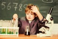 Toddler genius baby. Boy near microscope and test tubes in school classroom. Technology and science concept. Kid study