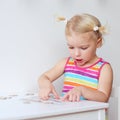 Toddler girl assembling jigsaw puzzle indoors