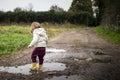 Toddler splashing in puddles in muddy country road Royalty Free Stock Photo