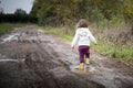 Toddler splashing in puddles in muddy country road Royalty Free Stock Photo