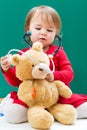 Toddler girl caring for her teddy bear with a stethoscope Royalty Free Stock Photo