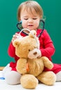 Toddler girl caring for her teddy bear with a stethoscope Royalty Free Stock Photo