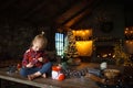 Little white blonde girl sitting on a wooden table in the living room of the Chalet, decorated for Christmas tree and garlands wit Royalty Free Stock Photo