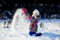 Toddler girl in colorful snowsuit plays in snow Royalty Free Stock Photo