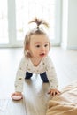 Toddler girl is crawling on floor in room. Concept of childhood, kindergarten and education Royalty Free Stock Photo