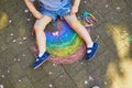 Toddler girl drawing rainbow with colorful chalks on asphalt Royalty Free Stock Photo