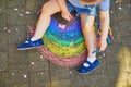 Toddler girl drawing rainbow with colorful chalks on asphalt Royalty Free Stock Photo