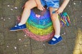 Toddler girl drawing rainbow with colorful chalks
