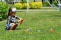 Toddler girl `fishing` on the sunlit summer lawn