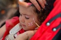 Toddler girl getting her face painted by face painting artist Royalty Free Stock Photo