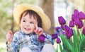 Toddler girl in a hat playing with tulips Royalty Free Stock Photo