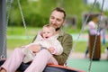 Toddler girl having fun on outdoor playground. Young father rides daughter on swing. Spring/summer/autumn active leisure for Royalty Free Stock Photo