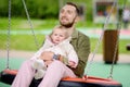 Toddler girl having fun on outdoor playground. Young father rides daughter on swing. Spring/summer/autumn active leisure for Royalty Free Stock Photo