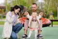 Toddler girl having fun on outdoor playground. Young parents is teaching his little daughter to walk. First step of baby Royalty Free Stock Photo
