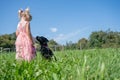 Toddler girl and her labrador puppy standing in green meadow Royalty Free Stock Photo