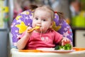 Toddler girl in a highchair for feeding with fork