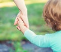 Toddler girl holding hands with her parent