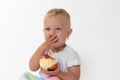 Toddler girl holding red apple is covering her mouth with hand Royalty Free Stock Photo