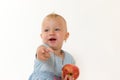 Toddler girl is holding red apple and pointing her finger at the Royalty Free Stock Photo