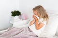 Toddler girl is lying in bed. The child is cold and sick and has a runny nose and snot. The child wipes his nose with a