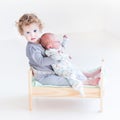Toddler girl with newborn baby brother in toy bed Royalty Free Stock Photo