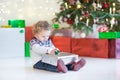 Toddler girl opening her Christmas present under Christmas tree Royalty Free Stock Photo