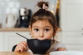 toddler girl picky eater at home kitchen. learning o eat with spoon. bad table manners of kid