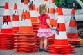 Toddler girl playing with many safety traffic cones on the street Royalty Free Stock Photo