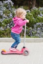 Toddler girl on a scooter in a park Royalty Free Stock Photo