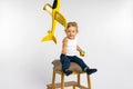 Toddler girl sits on stool and play yellow plane. Concept of gender stereotypes