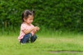 Toddler girl sitting and playing grass flower in field