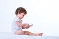 Toddler girl sitting and playing with mobile cellphone isolated on a white background Royalty Free Stock Photo