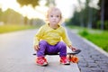 Toddler girl sitting on skateboard on summer street