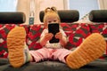 Toddler girl sitting on sofa, holding smarthphone and watching internet videos