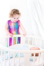 Toddler girl standing at round bed of her brother Royalty Free Stock Photo
