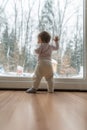 Toddler girl standing up against dirty window looking out Royalty Free Stock Photo