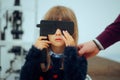 Little Patient Girl Holding a Lorgnette Pinhole occluder for Consultation