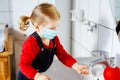 Toddler girl wear medical mask and cleaning, washing hands with soap and water. Child learning cleaning body parts