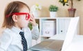 Toddler girl wearing big red glasses while using her laptop Royalty Free Stock Photo