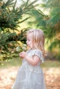 Toddler Girl in White Lace Dress in the Garden Smelling Flowers