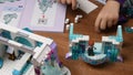 Toddler hand puts toy Lego blocks on table and plays Frozen Disney castle