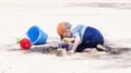 Toddler with Hat & Sunglasses Plays on a Sandy Beach Building Sand Castles Royalty Free Stock Photo